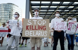A protester holds a sign reading "Stop Killing Belarus" during a demonstration on the contested elections in Belarus in Berlin, on August 15, 2020. - The opposition in Belarus keeps up the pressure on President Alexander Lukashenko with a fresh demonstration in Minsk on August 15, as the strongman reached out to Russia in an apparent plea for help. (Photo by John MACDOUGALL / AFP)