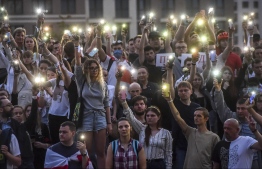 Belarus opposition supporters raise their mobile phones with flashlights during a symbolic minute of silence near the State TV and radio company during a protest rally against police violence recent rallies of opposition supporters, who accuse strongman Alexander Lukashenko of falsifying the polls in the presidential election, in central Minsk on August 15, 2020. (Photo by Sergei GAPON / AFP)