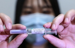 A staff member holds up a sample of a potential COVID-19 vaccine at a production plant of SinoPharm in Beijing. (AP)