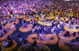 (FILES) This file photo taken on August 15, 2020 shows people watching a performance as they cool off in a swimming pool in Wuhan in China's central Hubei province. - The massive pool party attended by thousands of people at the epicentre of the COVID-19 coronavirus pandemic showed how well China had dealt with disease, authorities insisted on August 20, 2020, despite images from the event prompting outrage around the world. (Photo by STR / AFP) / 