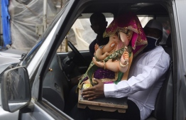 Devotees transport an idol of elephant headed Hindu god Ganesha in a car on the first day of the Ganesh Chaturthi festival, in Mumbai on August 22, 2020. - India's much-loved Ganesha festival opened to a muted reception on August 22 as tough COVID-19 coronavirus restrictions prevented devotees from holding grand celebrations and carrying out traditional rituals to honour the Hindu elephant god. (Photo by Punit PARANJPE / AFP)