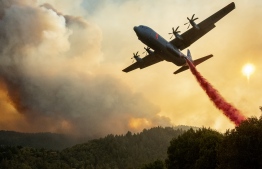 An aircraft drops fire retardant on a ridge during the Walbridge fire, part of the larger LNU Lightning Complex fire as flames continue to spread in Healdsburg, California on August 20, 2020. - A series of massive fires in northern and central California forced more evacuations as they quickly spread August 20, darkening the skies and dangerously affecting air quality. (Photo by JOSH EDELSON / AFP)