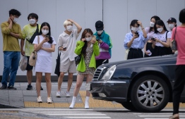 Pedestrians wearing face masks wait to cross a street in Seoul on August 24, 2020. - South Korea ramped up coronavirus restrictions on August 23 to try to contain a growing outbreak, as many countries around the world battled worrying surges in infections. (Photo by Ed JONES / AFP)