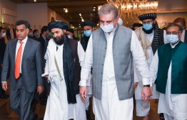 In this handout photograph taken on August 25, 2020, and released by the Pakistan Foreign Ministry, Pakistan's Foreign Minister Shah Mehmood Qureshi (3R) walks with Taliban co-founder Mullah Abdul Ghani Baradar (2L) upon his arrival with the delegation for talks at the Pakistan Foreign Ministry in Islamabad. - Pakistan has invited key Taliban negotiators to its capital to push for peace talks to end the conflict in neighbouring Afghanistan, Islamabad's foreign minister said August 24. (Photo by Handout / Pakistan Foreign Ministry / AFP) / 