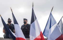 Police officers with protective mask stand guard near French flags during the etablishment ceremony of the new prefect of the Pays-de-la-Loire region and of the Loire-Atlantique department, on August 24, 2020 in Nantes, western France. (Photo by Loic VENANCE / AFP)