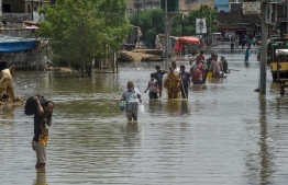 People wade through a flooded residential area after heavy monsoon rains triggered floods in Pakistan's port city of Karachi on August 28, 2020. (Photo by Asif Hassan/ AFP)