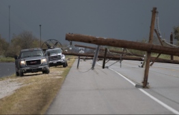 People trying to reach their homes in Cameron parish drive past downed power lines after the passing of Hurricane Laura south of Lake Charles, Louisiana on August 28, 2020. - At least six people were killed by Hurricane Laura in Louisiana and search teams may find more victims, but the governor said on August 27 that the most powerful storm to make landfall in the US state in living memory did not cause the "catastrophic" damage that had been feared. (Photo by ANDREW CABALLERO-REYNOLDS / AFP)