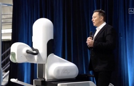 This video grab made from the online Neuralink livestream shows Elon Musk standing next to the surgical robot during his Neuralink presentation on August 28, 2020. - Futurist entrepreneur Elon Musk late August 28 demonstrated progress made by his Neuralink startup in meshing brains with computers, saying the work is vital to the future of humanity. (Photo by - / Neuralink / AFP) / 