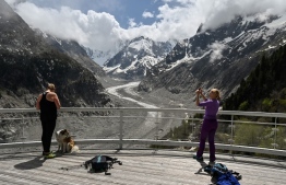 (FILES) This file photo taken on May 16, 2020 shows tourists wearing face masks posing in front of the panorama of the 'Mer de glace' (Sea of Ice) glacier near Chamonix Mont-Blanc, eastern France. (Photo by PHILIPPE DESMAZES / AFP)