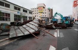 A clean-up crew works to remove roofs which were blown off into a street by strong winds brought by Typhoon Haishen in Fukuoka as the storm passes the southern Japanese island of Kyushu on September 7, 2020. - Powerful Typhoon Haishen approached South Korea on September 7 after slamming southern Japan with record winds and heavy rains that prompted evacuation warnings for millions. (Photo by STR / JIJI PRESS / AFP) / 