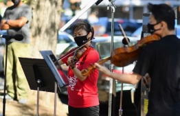 Violinist Quan Ge (L) and violist Cong Wu of the New York Philharmonic play with their 'bandwagon's pop-up concert series' at Betty Carter Park on September 04, 2020, in the Brooklyn Borough of New York City. - Its fall season has been cancelled and its concert hall closed indefinitely, so New York's Philharmonic is taking it to the streets. One of America's oldest musical institutions, the famed symphony orchestra is playing outdoor pop-up shows, getting creative during the coronavirus pandemic that has kept concert halls closed and New Yorkers starved for live music. (Photo by Angela Weiss / AFP)
