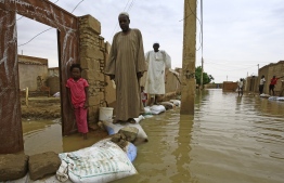 Sudanese residents walk on sandbags to reach their houses along a flooded street in the capital Khartoum's southern neighbourhood of al-Kalakla, on August 31, 2020. - Sudan on September 5 declared the imposition of a three-month state of emergency nationwide after record-breaking torrential floods caused by more than a month heavy rains left dozens dead and 100,000 damaged properties in their wake, in one of the worst natural disasters in decades, according to state news agency SUNA. (Photo by ASHRAF SHAZLY / AFP)
