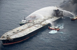 This handout photograph taken on September 8, 2020, and released by Sri Lanka's Air Force shows fireboats battling to extinguish a fire on the Panamanian-registered crude oil tanker New Diamond, some 60 km off Sri Lanka's eastern coast where a fire was reported inside the engine room. - India on September 8 sent fresh supplies of firefighting chemicals to help battle a new blaze on a stricken tanker loaded with a massive cargo of crude oil off Sri Lanka's eastern coast. (Photo by - / Sri Lankan Air Force / AFP) / 