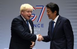 (FILES) In this file photo taken on August 26, 2019 Britain's Prime Minister Boris Johnson (L) shakes hands with Japan's Prime Minister Shinzo Abe (R) ahead of a bilateral meeting during the annual G7 summit in Biarritz, south-western France on August 26, 2019. - Britain on September 11, 2020 announced that it had secured a free trade deal with Japan, the country's first major post-Brexit agreement. (Photo by NEIL HALL / POOL / AFP)