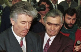 In this photo, taken on January 9 in 1996,  kBosnian Serb wartime leader Radovan Karadzic, left, and Serb member of Bosnian Presidency Momcilo Krajisnik roll the cake, marking St. Stevan, Republic of Srpska patron-saint day, in the Bosnian town of Pale. The hospital in the northern Bosnian town of Banja Luka said Monday, Sept. 14, 2020, that Krajisnik, a former top wartime Bosnian Serb official who was convicted of war crimes by a U.N. court, died after contracting the new coronavirus. He was 75. PHOTO: DARKO VOJINOVIC /AP