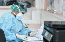 A health professional reviews documents while wearing Personal Protective Equipment. PHOTO: NISHAN ALI/ MIHAARU