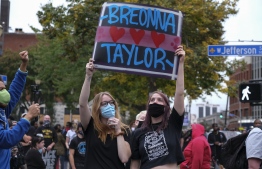 Protestors hold a sign while marching in downtown Louisville, Kentucky, on September 23, 2020, after a judge announced the charges brought by a grand jury against Detective Brett Hankison, one of three police officers involved in the fatal shooting of Breonna Taylor in March. - Hankison was charged today, September 23, with three counts of "wanton endangerment" in connection with the shooting of  Taylor, a 26-year-old black woman whose name has become a rallying cry for the Black Lives Matter movement. (Photo by Jeff Dean / AFP)