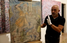 Gaby Maamary, a Lebanese artwork conservation specialist, examines a 19th-century painting, damaged in the Beirut port blast, at his studio in the capital Beirut on September 17, 2020. - The blast at the capital's port on August 4 killed more than 190 people, and wounded thousands more as it sent lethal shockwaves pummelling through the city. But it also ravaged dozens of the capital's mot cherished heritage buildings. (Photo by ANWAR AMRO / AFP)