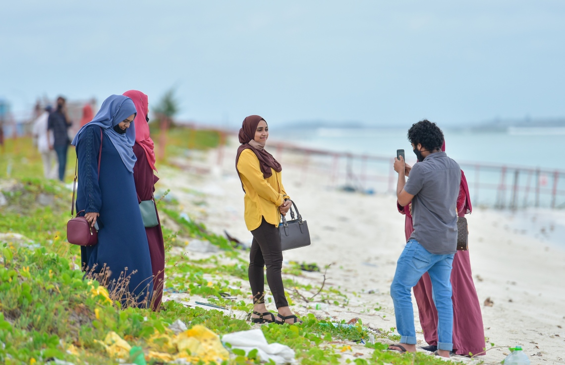 ހުޅުމާލެ: އޮކްޓޫބަރު 2، 2020- ހުޅުމާލޭގެ ދެވަނަ ފިޔަވަހި ބަލައިލަން މިއަދު ހަވީރު ދިޔަ މީހަކު ބީޗު ސަރަހައްދުގައި ފޮޓޯއެއް ނަގާއިރު، އެހެން ދެ މީހަކު އެ ތަނުގައި މަޑުކޮށްލައިގެން.---ފޮޓޯ: އަހުމަދު އަވްޝަން/މިހާރު