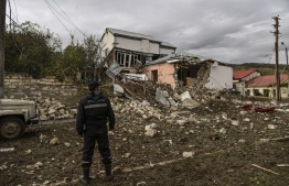 A man stands in front of a destroyed house after a late October 7 sheling in the breakaway Nagorno-Karabakh region's main city of Stepanakert on October 8, 2020, during the ongoing fighting between Armenia and Azerbaijan over the disputed region. (Photo by ARIS MESSINIS / AFP)