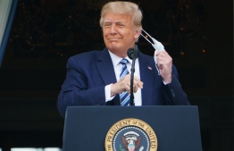 US President Donald Trump takes his mask off before speaking from the South Portico of the White House in Washington, DC during a rally on October 10, 2020. - Trump spoke publicly for the first time since testing positive for Covid-19, as he prepares a rapid return to the campaign trail just three weeks before the election. (Photo by MANDEL NGAN / AFP)