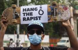 A Bangladeshi citizen holding up a skateboard calling for capital punishment for rapists. PHOTO: AFP
