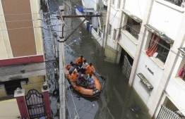 National Disaster Response Force (NDRF) personnel evacuate local residents in a boat along a flooded street following heavy rains in Hyderabad on October 15, 2020. (Photo by NOAH SEELAM / AFP)