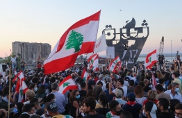Lebanese protesters gather to light the "October 17 torch" marking the one year anniversary of the beginning of a nationwide anti-government protest movement, in front of the devastated port of the capital Beirut where a massive explosion took place more than two months ago, on October 17, 2020. - Hundreds marched in Lebanon's capital to mark the first anniversary of a non-sectarian protest movement that has rocked the political elite but has yet to achieve its goal of sweeping reform. (Photo by ANWAR AMRO / AFP)
