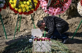 A man mourns above a grave of a fellow fighter in Stepanakert during fighting over the breakaway region of Nagorno-Karabakh on October 17, 2020. - Azerbaijan's President Ilham Aliyev vowed on October 17, 2020 to take revenge on Armenia after a missile strike killed 12 sleeping people in the city of Ganja, a dramatic escalation in the conflict over the disputed Nagorno-Karabakh region. (Photo by ARIS MESSINIS / AFP)