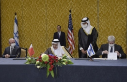 US Treasury Secretary Steve Mnuchin (back) attends a signing ceremony between the head of the Israeli delegation, National Security Advisor Meir Ben Shabbat (L) and Bahraini Foreign Minister Abdullatif bin Rashid Al-Zayani (C), in the Bahraini capital Manama on October 18, 2020. - Israel and Bahrain cemented a deal officially establishing relations and signed several memorandums of understanding, further opening up the wealthy Gulf region to the Jewish state. (Photo by Mazen Mahdi / AFP)