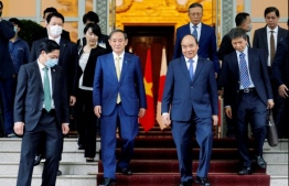 Japan's Prime Minister Yoshihide Suga (centre L) and Vietnam's Prime Minister Nguyen Xuan Phuc (centre R) walk together after a press briefing at Government Office in Hanoi on October 19, 2020. (Photo by Minh HOANG / POOL / AFP)