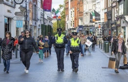 Police officers patrol a busy Grafton Street in Dublin on October 21, 2020 as Ireland prepares to enter a second national lockdown to stem the spread of the virus that causes Covid-19. - Millions of people in Ireland were getting set for a second national lockdown on October 21, the first European country to take the drastic step as the continent battles a persistent surge in coronavirus cases. (Photo by Paul Faith / AFP)