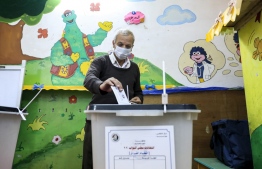 A man, mask-clad due to the COVID-19 coronavirus pandemic, casts his vote at a polling station in the Agouza district in Giza, the twin-city of Egypt's capital, on October 24, 2020, while voting in the first stage of the lower house elections. - Polling stations opened in Egypt for parliamentary elections in which there was little doubt of a sweeping victory for supporters of hardline President Abdel Fattah al-Sissi. Some 63 million voters out of Egypt's more than 100 million people are eligible to elect 568 of the 596 lawmakers in the lower house, widely seen as a rubber-stamp body for executive policies. (Photo by Khaled DESOUKI / AFP)