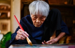 This photograph taken on October 8, 2020 shows 89-year-old Vietnamese artist Mong Bich painting at her house in Bac Ninh province, east of Hanoi. - Bich specialises in silk paintings of daily life and ordinary people, women in particular, and ploughed a lonely furrow during many years of war when artists were steered towards the army or frontline workers as subjects. (Photo by Manan VATSYAYANA / AFP) / 