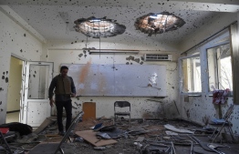 A journalist walks inside of a damaged class of the National Legal Training center, a day after gunmen stormed Kabul university in Kabul on November 3, 2020. - Stunned students demonstrated outside Kabul University on November 3 after at least 22 people were killed in a brutal, on-campus attack claimed by the Islamic State group. (Photo by WAKIL KOHSAR / AFP)