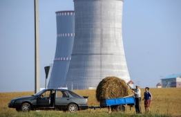 (FILES) In this file photo taken on August 19, 2017, people transport a bundle of straw close to the construction site of the first Belarus' nuclear power plant outside the town of Ostrovets, some 170 km northwest of Minsk. - Belarus on November 3, 2020 launched its controversial Russia-built nuclear power station despite safety concerns from neighbouring Baltic states three decades after the Chernobyl nuclear disaster. (Photo by Sergei GAPON / AFP)