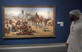 An Emirati man, wearing a protective mask due to the COVID-19 pandemic, visits Sharjah Art Museum on August 24, 2020. - From creations depicting the killing of Palestinians to the daily lives of those who lived in Yemen's old city of Sanaa, paintings by Arab artists come to life in the Gulf emirate of Sharjah. Sharjah is one of the seven emirates that make up the United Arab Emirates, whose capital Abu Dhabi and freewheeling Dubai are better known for ultra-luxurious hotels, mega malls and global events. In recent years the UAE has poured huge sums into culture, including the Louvre Abu Dhabi, a branch of the Paris museum which opened in 2017. (Photo by Karim SAHIB / AFP)