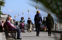 People wearing protective face masks, walk along the promenade of Varazze, a village in the Italy's northern region of Liguria, on November 5, 2020. PHOTO: VINCENZO PINTO/ AFP