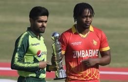 Pakistan's captain Babar Azam (L) and Zimbabwe's captain Chamu Chibhabha hold the trophy of Twenty20 three-match series at the Rawalpindi Cricket Stadium in Rawalpindi on November 7, 2020. (Photo by Aamir QURESHI / AFP)