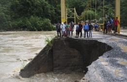 People look at the damage caused by heavy rains brought by Hurricane Eta, now degraded to a tropical storm, on a bridge over the overflooded Cahaboncito river in Panzos, Alta Verapaz, 220 km north of Guatemala City on November 6, 2020. - About 150 people have either died or remain unaccounted for in Guatemala due to mudslides caused by powerful storm Eta, which buried an entire village, President Alejandro Giammattei said Friday. (Photo by Johan ORDONEZ / AFP)