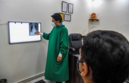 In this picture taken on November 5, 2020, lung specialist Davinder Kundra (L) checks an xray of a patient at his Breathe Better clinic in New Delhi. - A steady stream of patients are coming out of New Delhi's brownish atmosphere for treatment at the Breathe Better clinic where lung specialist Davinder Kundra is confronting what he calls the "double whammy" of deadly smog and the coronavirus. (Photo by Prakash SINGH / AFP) / 