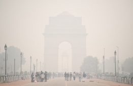 People walk along Rajpath near India Gate under heavy smog conditions in New Delhi on November 9, 2020. (Photo by Sajjad HUSSAIN / AFP)