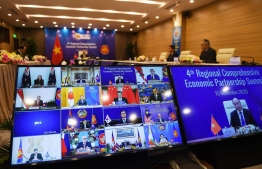Vietnam's Prime Minister Nguyen Xuan Phuc is pictured on the screen (R) as he addresses his counterparts during the 4th Regional Comprehensive Economic Partnership (RCEP) Summit at the Association of Southeast Asian Nations (ASEAN) summit being held online in Hanoi on November 15, 2020. (Photo by Nhac NGUYEN / AFP)
