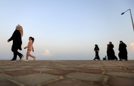 Palestinians walk on the Mediterranean beachfront promenade at dawn amid the COVID-19 pandemic, in Gaza City, on November 11, 2020. - At sunrise in Gaza, the strip's coastal path begins to fill up with pedestrians, as growing numbers of Palestinians have taken up walking to relieve stress inside the Israel-blockaded enclave. (Photo by MAHMUD HAMS / AFP)