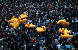 Large inflatable ducks are passed around the crowd as pro-democracy protesters gather for an anti-government rally at a major intersection in Bangkok on November 18, 2020. (Photo by Jack TAYLOR / AFP)