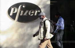 (FILES) In this file photo taken on November 11, 2020 People walk by the Pfizer world headquarters in New York. - Pfizer and its partner BioNTech confirmed they will apply on November 20, 2020, for emergency use authorization for their coronavirus vaccine, becoming the first to do so in the US or Europe as the pandemic rages around the world. The vaccine has been developed with breathtaking speed -- just 10 months after the genetic code of the novel coronavirus was first sequenced. (Photo by Kena Betancur / AFP)