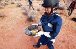 In this handout image from Japan Aerospace Exploration Agency (JAXA), a member of JAXA collects Hayabusa2's capsule carrying the first extensive samples of an asteroid after it landed in the Woomera restricted area, Australia, Sunday. PHOTO: JAXA