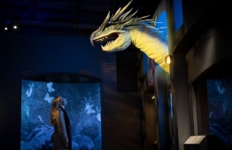 A member of staff poses with a prop of a Hungarian Horntail dragon made for the Fantastic Beasts film series at the press view of Fantastic Beasts: The Wonder of Nature exhibition at Natural History Exhibition in London on December 7, 2020. (Photo by Tolga Akmen / AFP) / EMBARGOED - NOT FOR USE ON ANY PLATFORM UNTIL WEDNESDAY DECEMBER 9, 2020 0001GMT