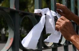A man ties a white ribbon on a fence at a cemetery as a sign of protest against the government policy of forced cremations of Muslims who die of the coronavirus, in Colombo December 14, 2020. - Sri Lanka said on December 9 it would cremate the bodies of 19 Muslim coronavirus victims, overriding the families' objections against the contentious policy. (Photo by LAKRUWAN WANNIARACHCHI / AFP)