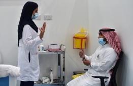 A nurse speaks to a man before administering the Pfizer-BioNTech COVID-19 coronavirus vaccine (Tozinameran), as part of a vaccination campaign by the Saudi health ministry, in Saudi Arabia's capital Riyadh on December 17, 2020. (Photo by FAYEZ NURELDINE / AFP)